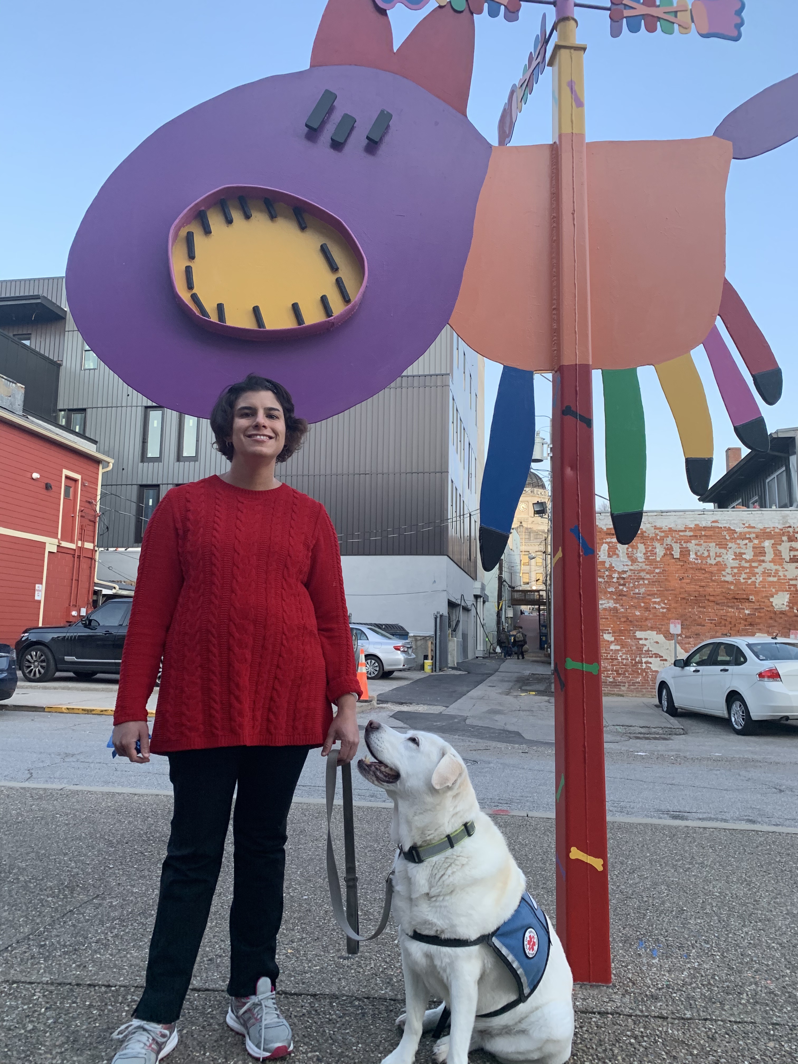 Adria Nassim with her service dog Lucy in front of an art sculpture in downtown Bloomington.