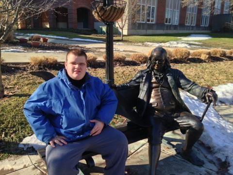Inspire student at Franklin College seated on bench next to statue of Ben Franklin.