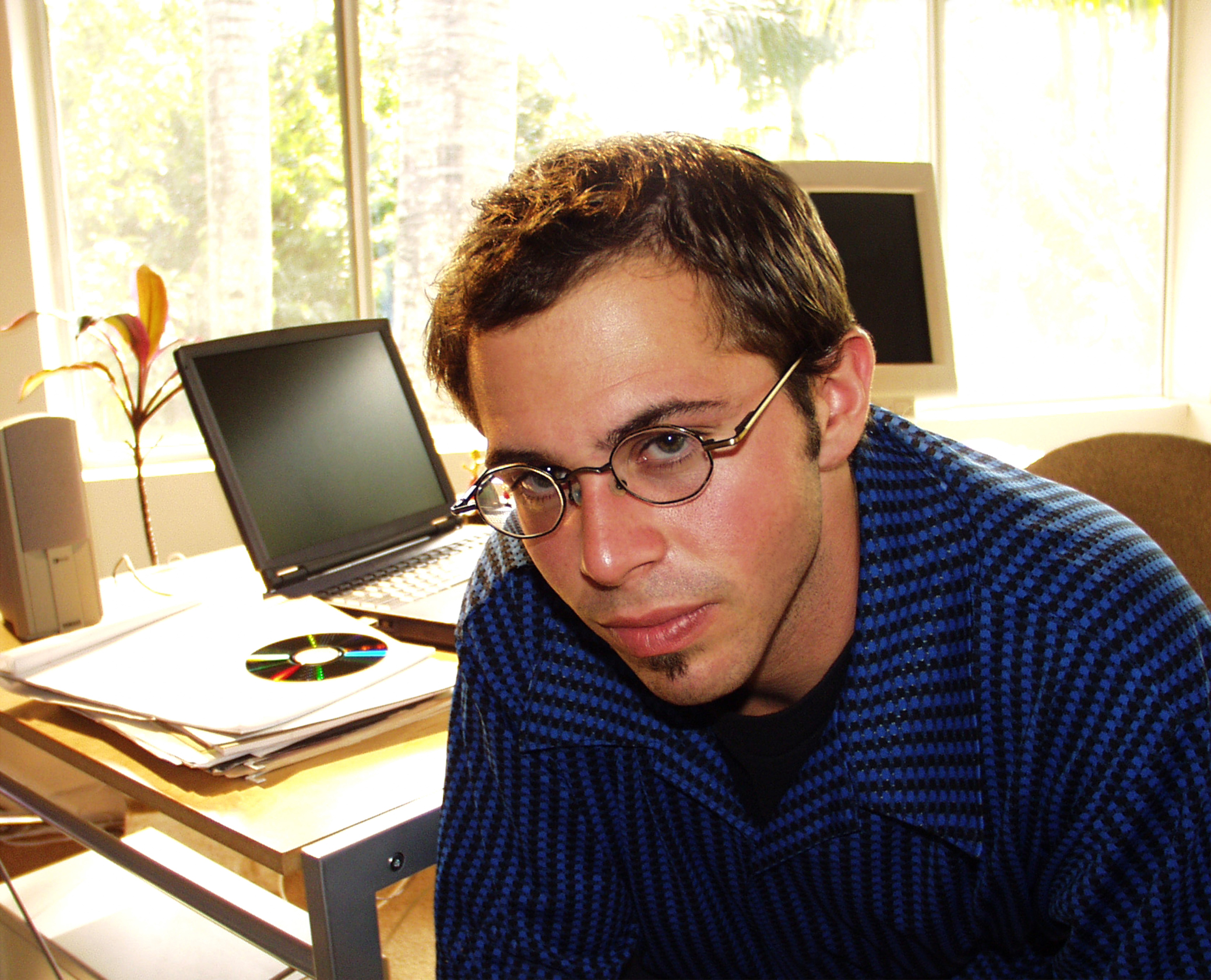 Young man at desk with laptop monitor in background.