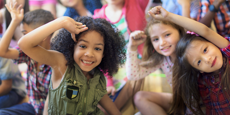 Happy preschool girls raising their hands.