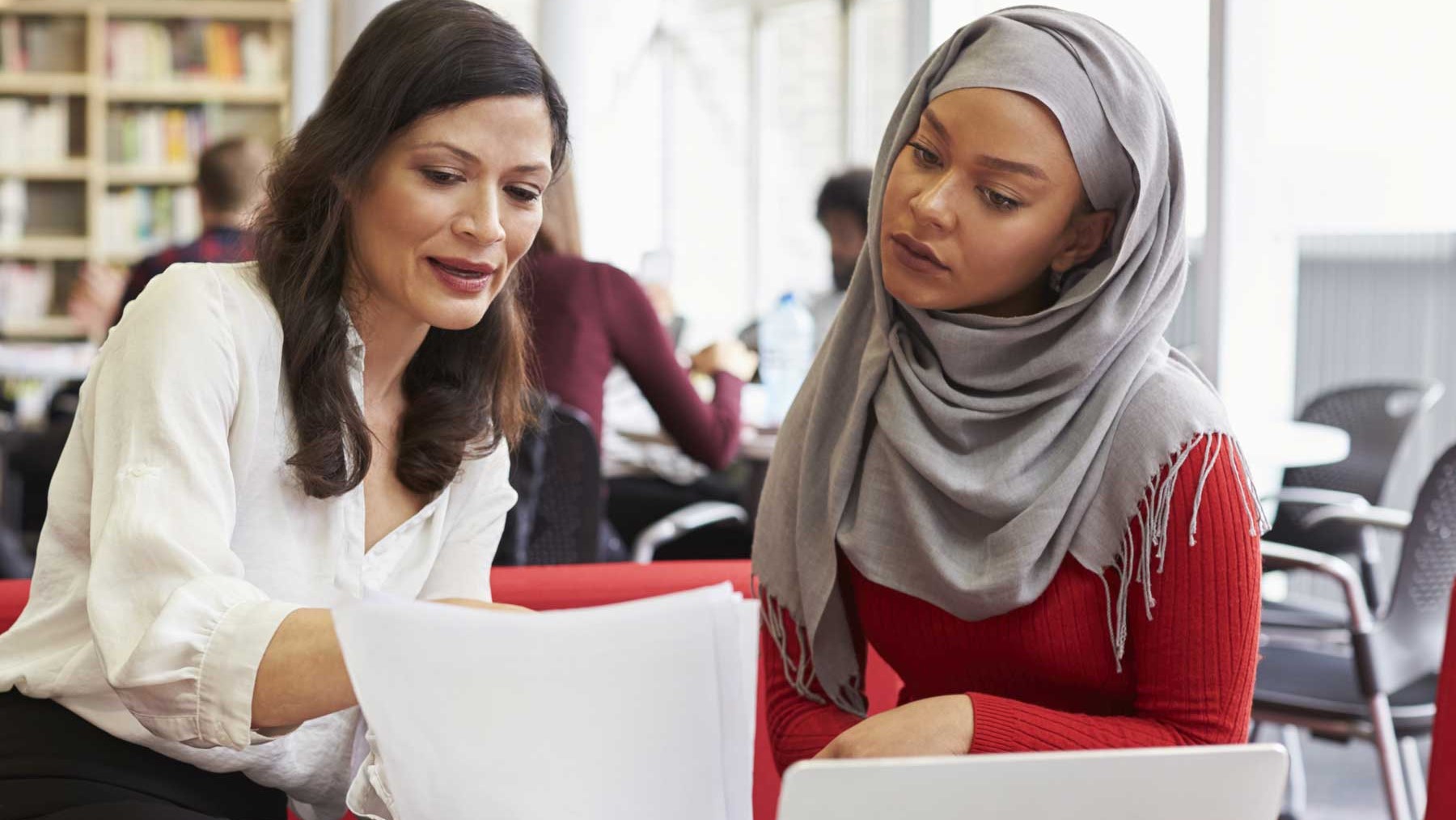 A female coach talking with a female teacher.