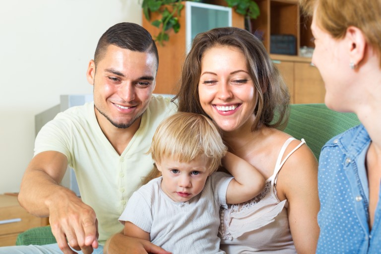 Home visitor meeting with two parents and their toddler.