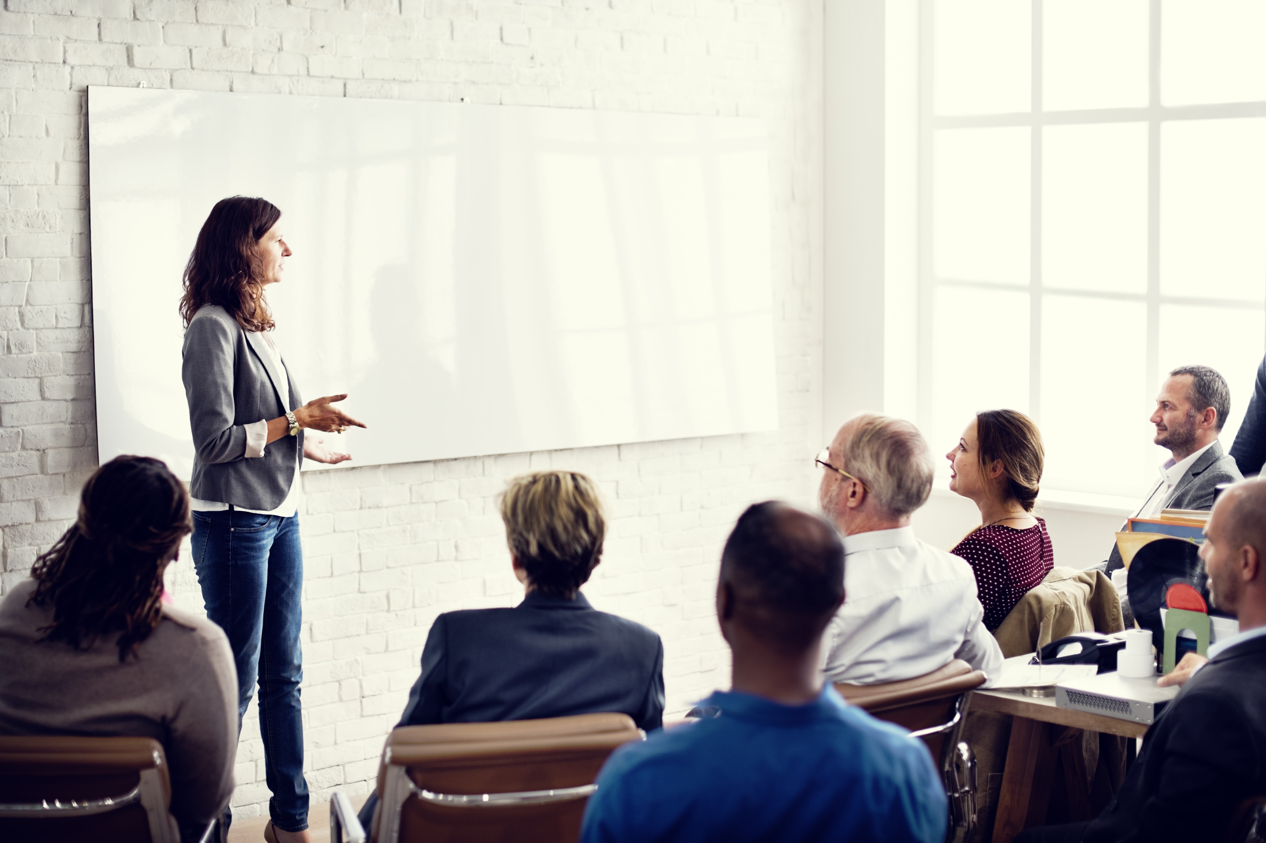 A female speaker presents to a room full of adults.